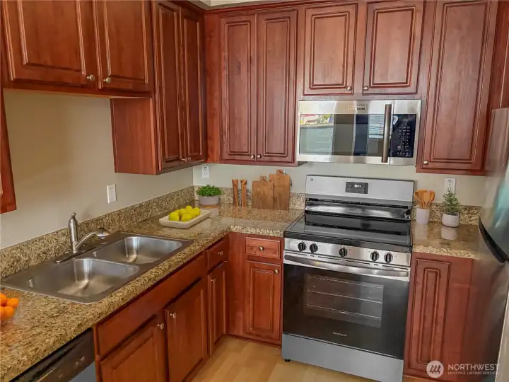 (Virtually Staged) Kitchen with granite countertops, stainless steel appliances, and classic wood cabinetry.