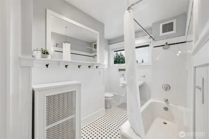 Bright second-floor guest bathroom with subway tile tub surround and pedestal sink