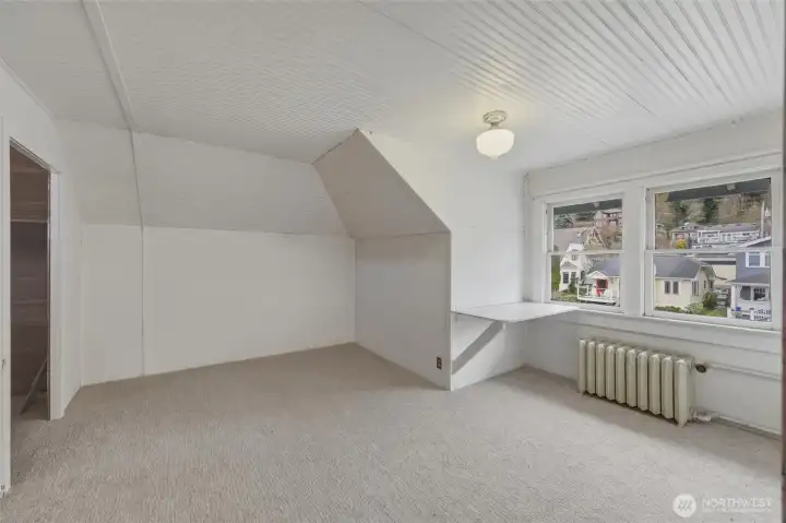 Third-level bedroom with dormer ceilings, built-in desk, and neighborhood outlook