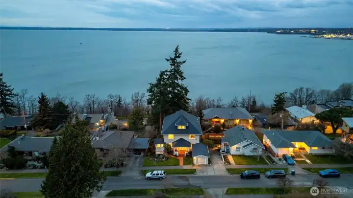 Twilight aerial showcasing the home’s elevated setting and sweeping bay views.