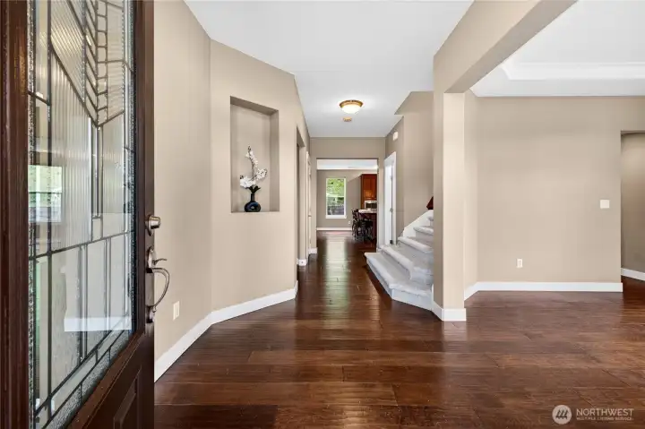 Elegant entry welcomes you with hardwood flooring, a display shelf, soaring ceilings, and a spacious coat closet
