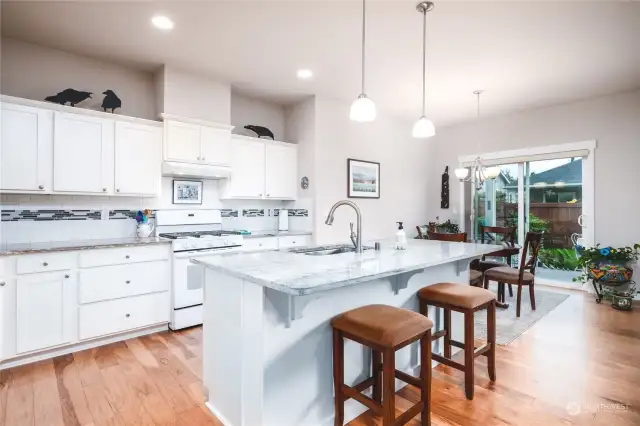 Black and white granite countertops, white subway tile backsplash with black and grey accents and white cabinetry create a clean, modern look.