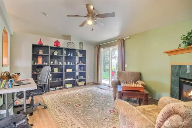 The spacious family room features a gas fireplace, ceiling fan and sliding doors leading to the large, terraced backyard