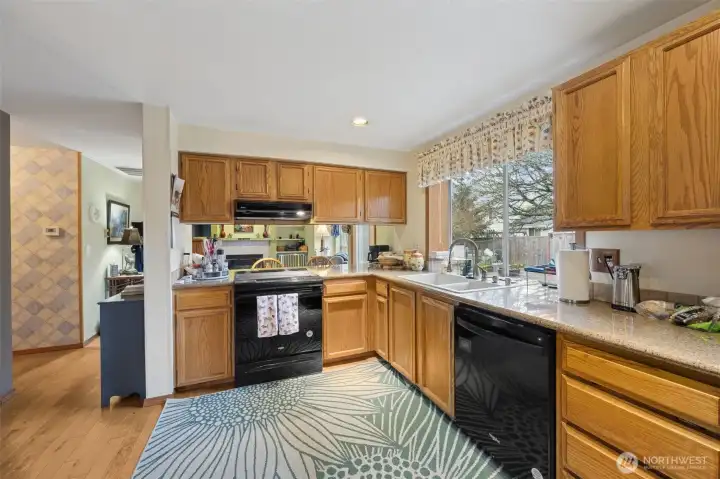 Updated kitchen with black appliances, slab granite countertops and hardwood floors. The look thru over the stove makes it easy for communications with guests in family room.