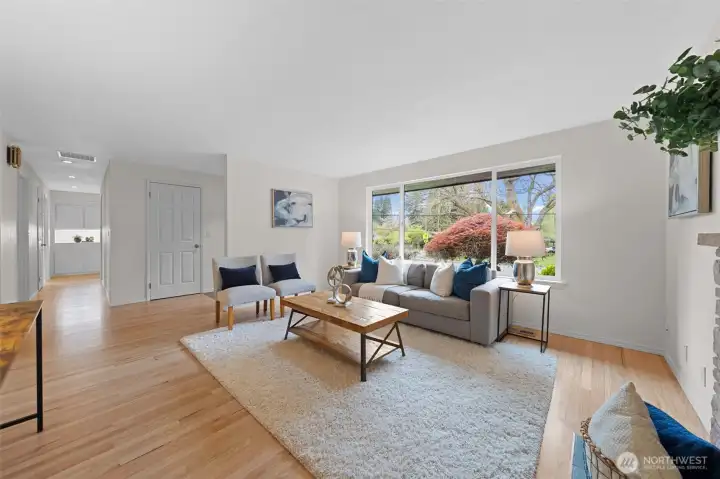 Light-filled living space with expansive windows overlooking mature landscaping. Open layout offers great flow and strong potential for modern updates.