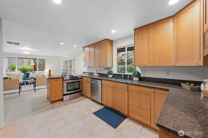 Expansive kitchen layout with abundant cabinetry, granite counters, and stainless steel appliances. Large window above the sink frames backyard views and brings natural light into the kitchen. Expansive kitchen layout with abundant cabinetry, granite counters, and stainless steel appliances. Large window above the sink frames backyard views and brings natural light into the kitchen.