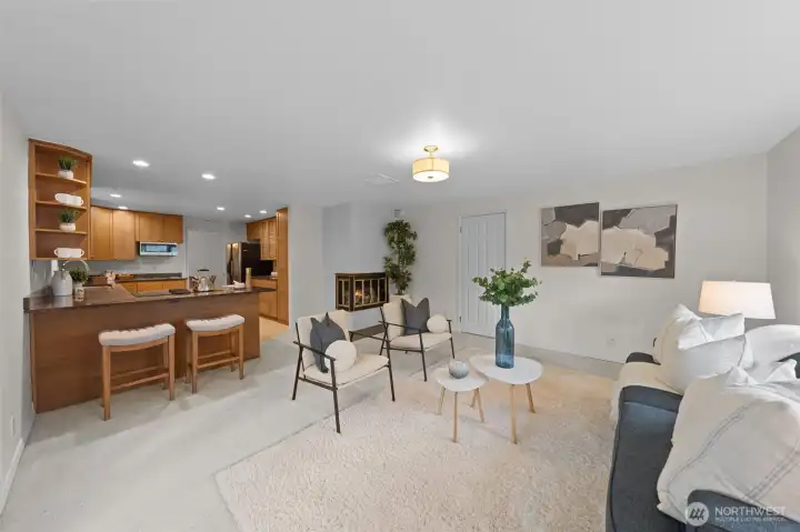 Open living area connects seamlessly to the kitchen with bar seating, creating an easy flow for gathering. Fireplace adds a focal point while the layout offers flexibility for seating and entertaining. The door to the right leads you to the utitlity room and garage.