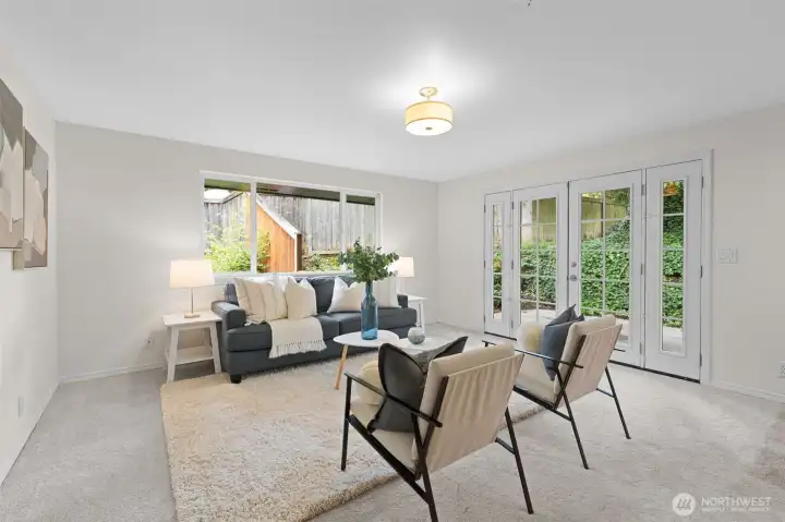 Living room with large window and French doors bringing in natural light and direct access to the outdoor patio. Spacious layout with defined seating area designed for comfort and conversation.