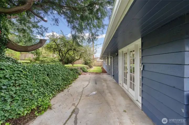 Private patio off the family room with direct French door access for easy indoor-outdoor flow. Surrounded by mature landscaping and greenery, offering space to relax or entertain.
