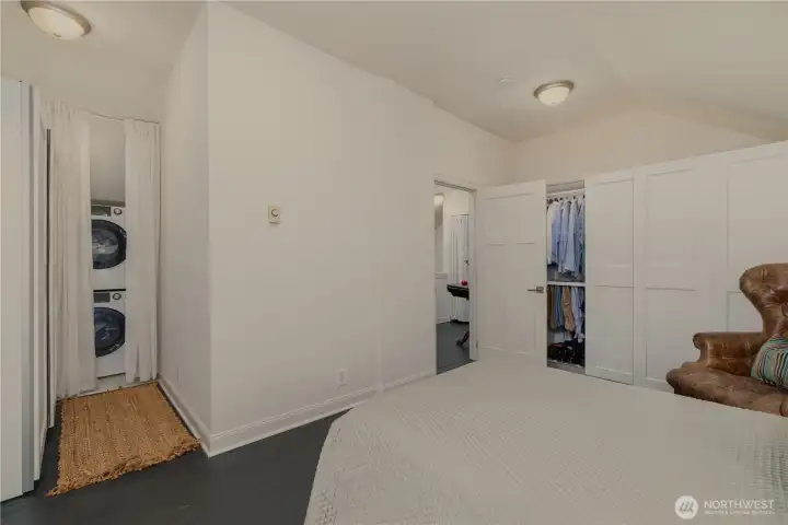 View of the back bedroom towards the door and landing. Wall of closets lead to the entry of the utility room with washer/ dryer. On the right side of the bedroom another wall of closets!