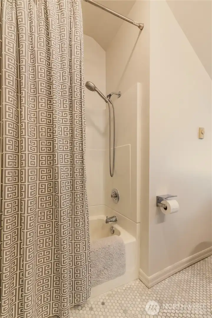 Off the landing, upstairs full bath with marble tiled floor and vaulted ceiling.