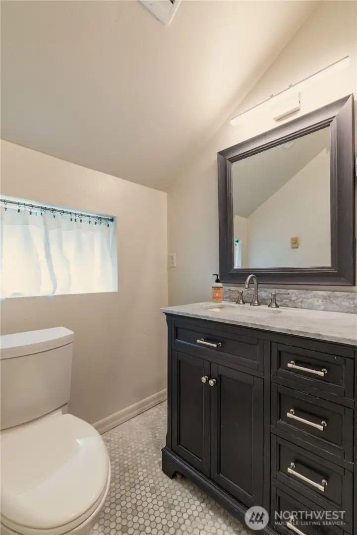 Upstairs full bath vanity with marble counter and sunny window.