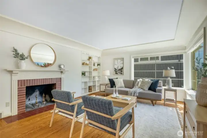Spacious, light-filled living room with coved ceilings, original millwork, wood-burning fireplace.