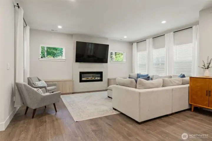 Gather and unwind in this sun-drenched great room where oversized windows flood the space with natural light. A sleek linear gas fireplace anchors the space with warmth and ambiance, while designer finishes and luxury flooring set the stage for everyday living.