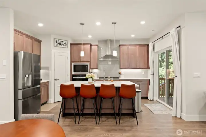 The heart of the home doesn't disappoint — a chef-inspired kitchen featuring rich cabinetry, quartz countertops, stainless steel appliances, and a generous center island with seating for four. Whether it's a weeknight dinner or a weekend gathering, this kitchen was made for making memories