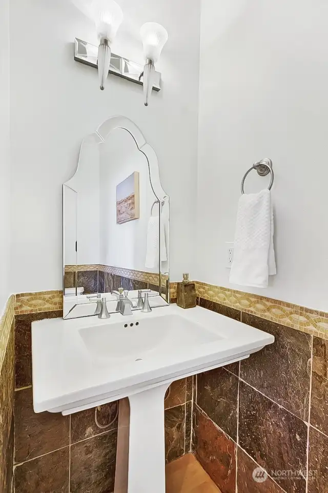 Main floor powder room with pedestal sink and travertine tiled walls.