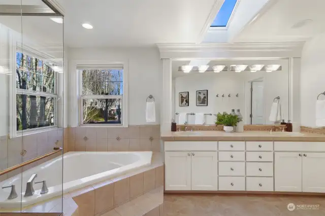 Ensuite primary bath with skylight, soaking tub, walk-in shower, tile floors and dual sinks.