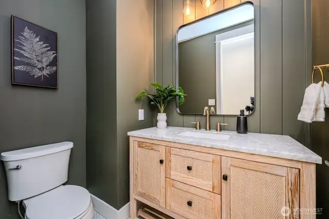 Moody, main floor powder room features this darling wicker hutch with quartz top, motion sensor lighting and brushed gold accents.