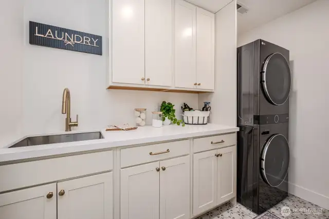 Laundry day just got an upgrade-- with quartz counters, ample storage in soft close cabinetry, a deep, stainless steel utility sink and stunning designer tile underfoot. This space blends elegance with everyday ease.