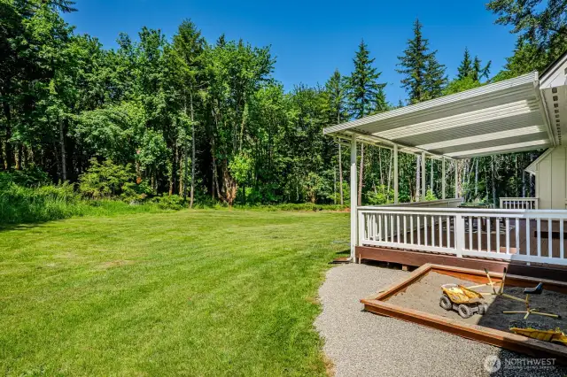 Backyard retreat with lawn space, sandbox and access to trails.