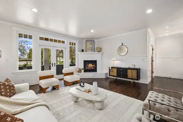 The formal living room is a showpiece--a grand, light-filled space framed by walls of windows. French doors open to a front porch, while a gas fireplace adds warmth and charm, creating the perfect setting for both entertaining and quiet evenings.