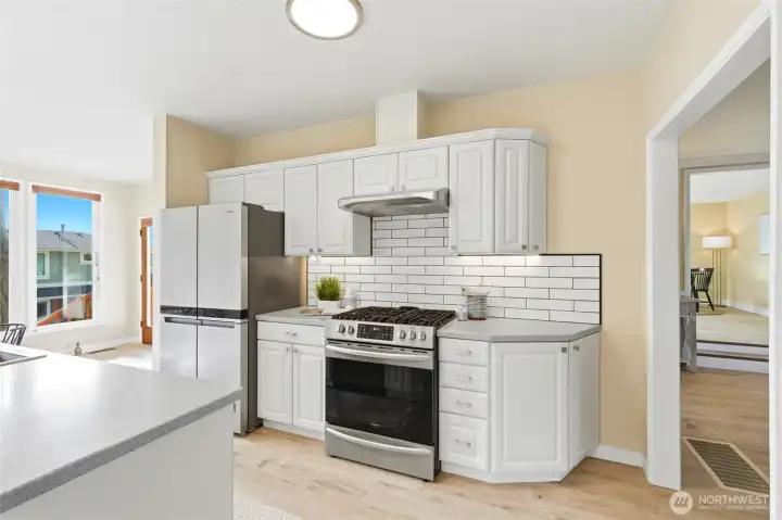 Updated kitchen with stainless steel appliances and tile backsplash.