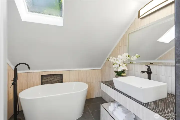 Freestanding soaking tub & skylight in the updated primary bathroom.
