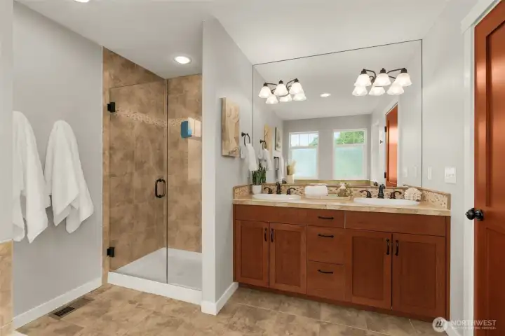 Double vanity and glass shower in the primary suite bathroom.