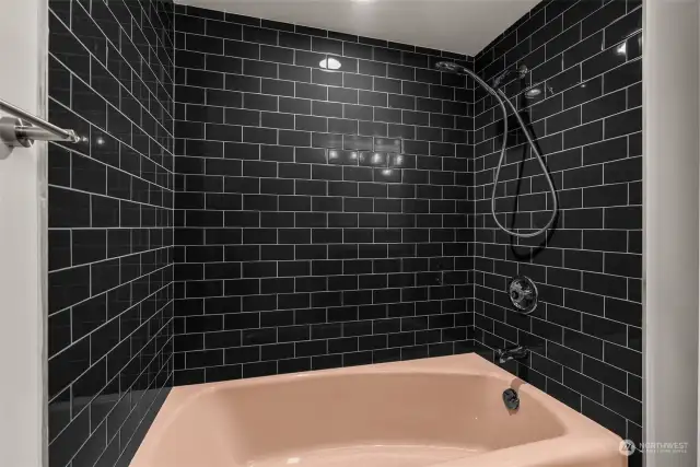 The black subway tile is sleek; the bathtub is perfectly appointed.