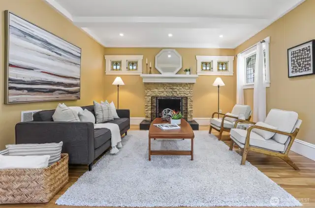 Inviting living room centered around a cozy wood-burning fireplace, framed by beautiful stained-glass windows that add timeless charm.