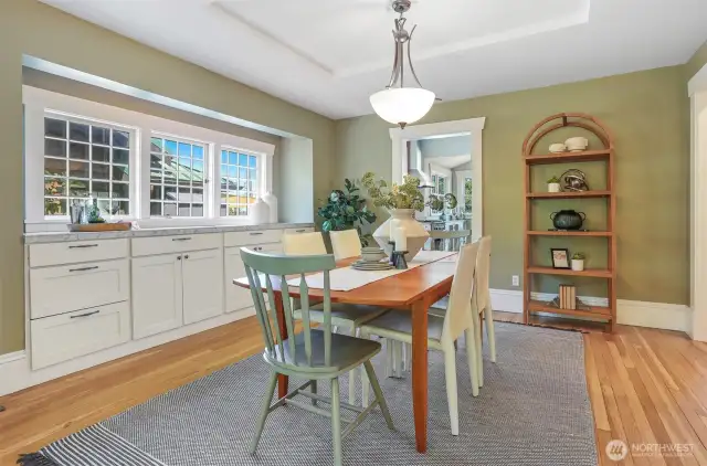 The formal dining room offers ample space for gatherings, with charming built-ins and a generous serving area highlighted by the original windows.