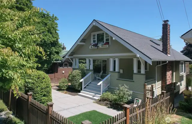 Enjoy a fully fenced yard with mature trees, thoughtful landscaping, low-maintenance hardscape, and a stunning Klinker brick fireplace as the showpiece.