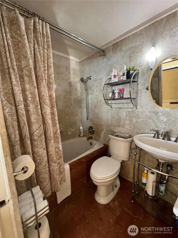 Upstairs bath has a jetted tub and marble floors.