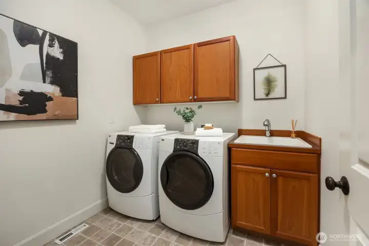A spacious main floor laundry room, appointed with storage cabinets and utiltiy sink.
