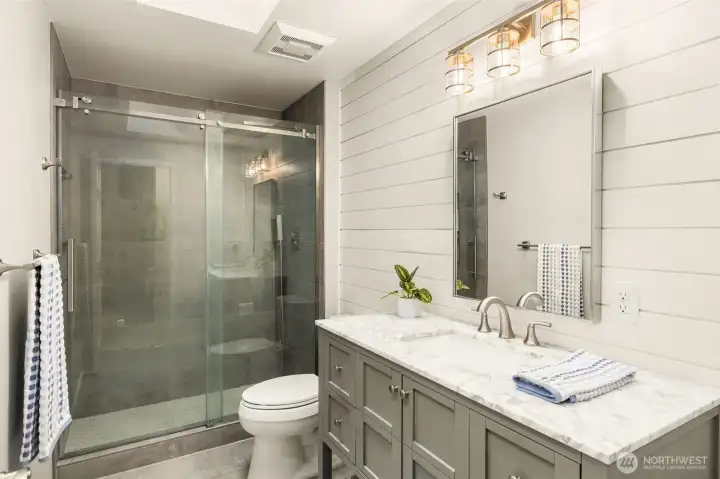 Upstairs hall bath is stylishly updated with a new vanity, floors, shower and shiplap wall