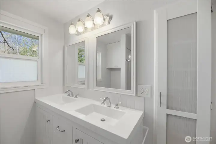 Bright bathroom with double vanity and large window for warm natural light.