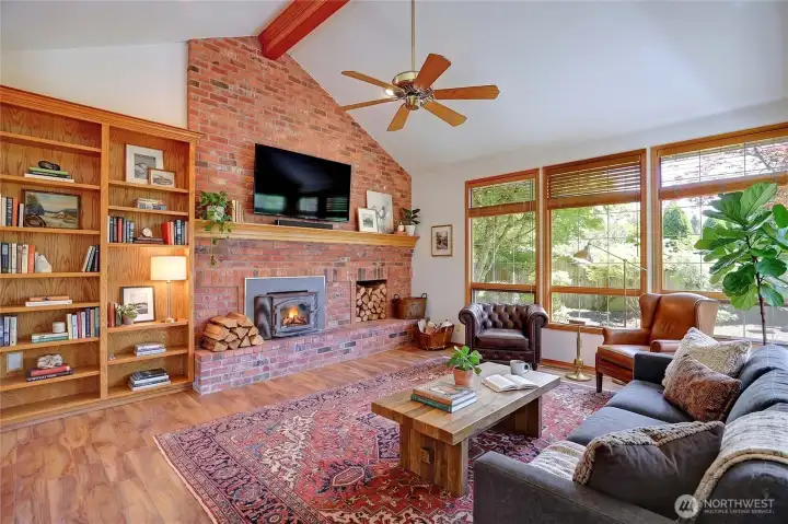 Virtually staged great room featuring built in shelving and brick hearth with wood burnuing fire insert