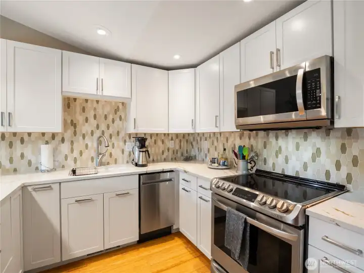 The white on white kitchen with stainless steel appliances is classic and have hexagonal tiles for interest on the back splash.