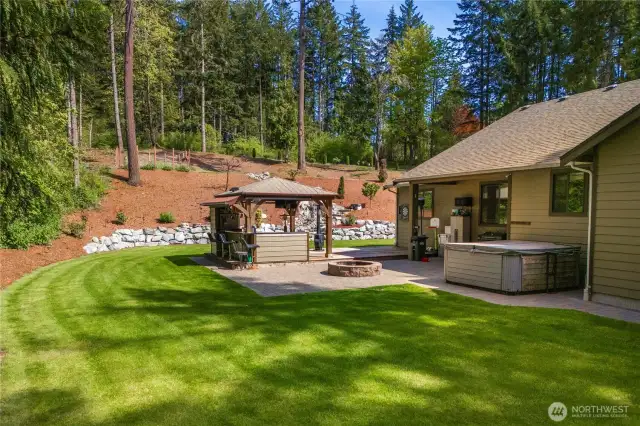 Peaceful backyard with outdoor kitchen, firepit and hot tub.