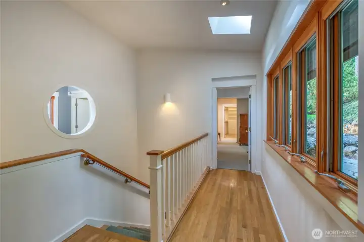 Hallway to primary bedroom and stairs to guest suites, rec room, storage, and wine room.