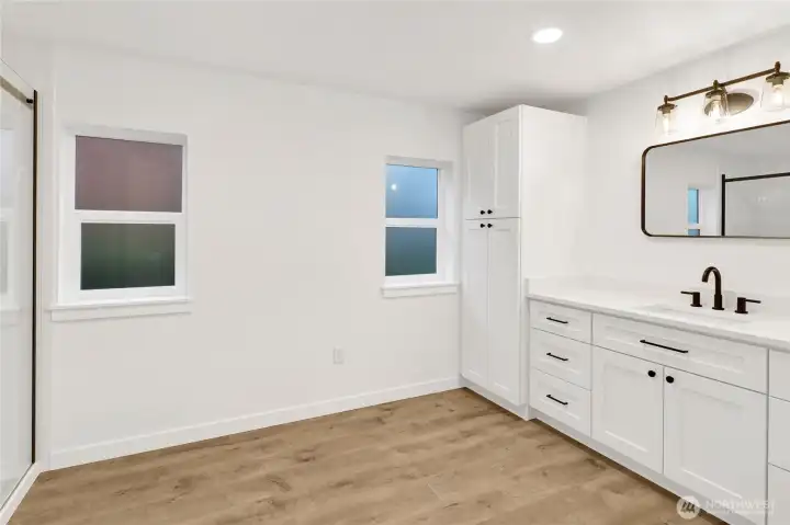 Stylish primary bathroom vanity with quartz counters, custom cabinetry, and modern lighting.