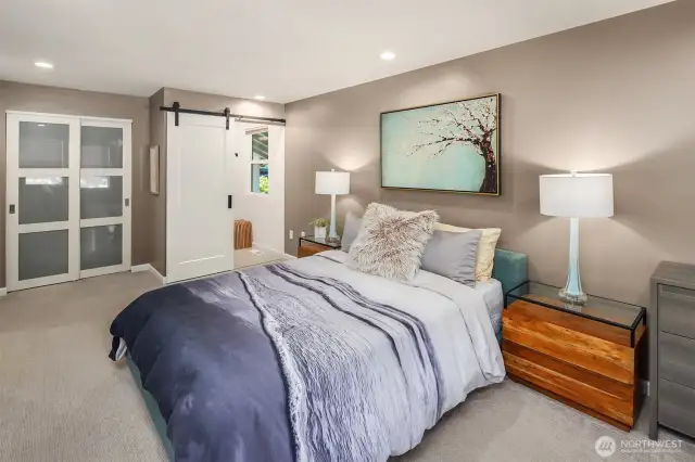 The spacious primary suite offers a peaceful retreat, featuring large windows that bathe the room in natural light, a full wall of closet space, and tranquil views of the landscaped backyard—perfect for unwinding after a long day.