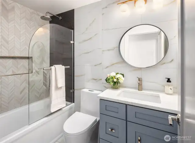 The stylish primary en-suite bathroom features dual vanities with updated hardware, ample counter space, and designer lighting. A shower-tub combo provides both functionality and relaxation, complemented by ceramic tile flooring.
