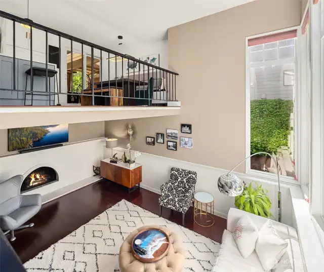 The main-level living room welcomes guests with large picture windows that frame lush outdoor views. A central wood-burning fireplace adds warmth and character, creating an ideal gathering spot year-round.