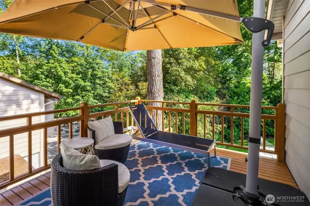 Relax and unwind on this private, tree-lined deck featuring all-day shade from a large umbrella, cozy lounge seating, and a stylish outdoor rug. Ideal for morning coffee or evening cocktails, this peaceful retreat offers a perfect blend of comfort and nature.