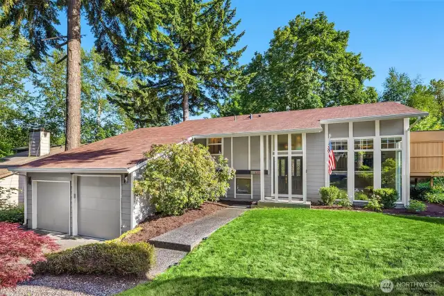 A beautifully maintained two-story home stands proudly, framed by mature landscaping and a manicured front lawn. The exterior showcases clean, timeless architecture with a charming covered porch, crisp trim details, and a tasteful blend of siding and stone accents.