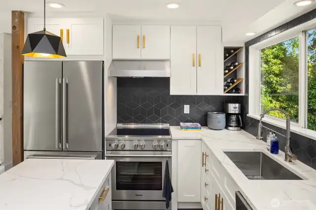 The kitchen is a functional showpiece with gleaming stainless steel appliances, solid-surface countertops, full-height backsplash, and rich cabinetry. An open layout connects effortlessly to dining and living areas for seamless entertaining.
