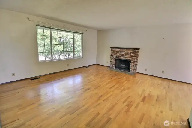 Spacious living room with original hardwood floor. Fireplace with gas log lighter.