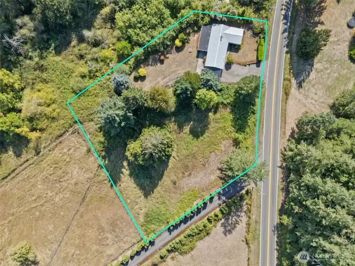 This aerial makes it easy to see how the property is divided: the home sits toward the top with lawn and gardens flowing behind, then the tree line opens up to usable pastureland. It’s space that’s already functional with room to grow.