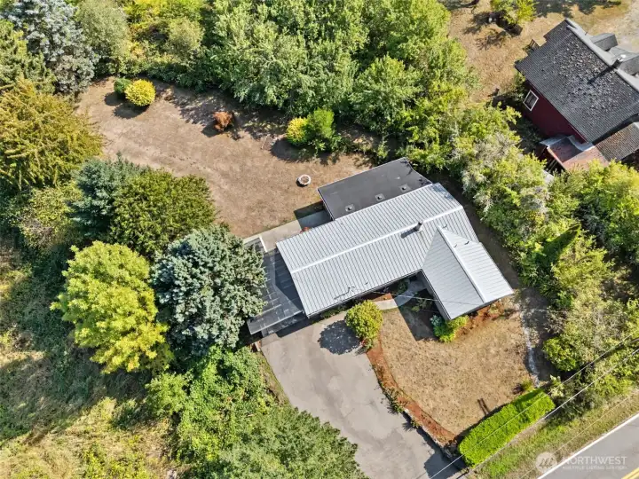 From above, you see the house topped with a metal roof, the gold standard for durability. It shrugs off storms, never needs replacing every couple of decades, and gives you actual peace of mind. Down below, the extra-wide gravel driveway proves just as reliable, with room for cars, guests, RVs, and the boat without a single shuffle game.